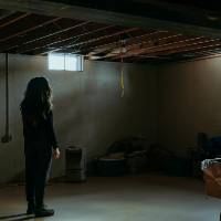 Lone woman standing in darkened basement